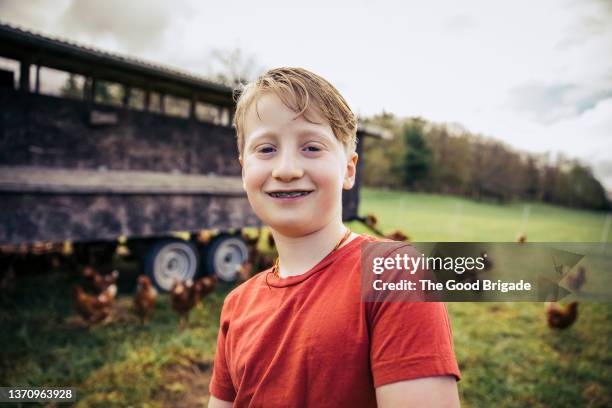 portrait of cheerful boy standing near chicken coop on farm - boys with braces stock pictures, royalty-free photos & images