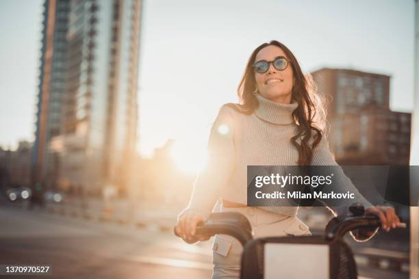 eine moderne, zeitgenössische junge frau tourt mit einem elektrofahrrad durch die stadt - velofahren stock-fotos und bilder