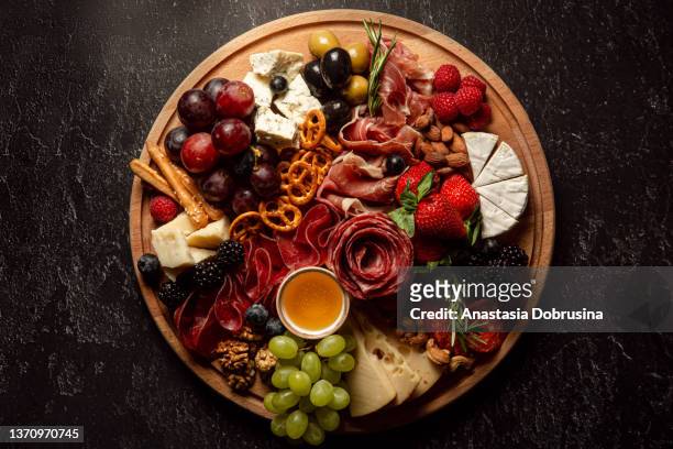 assortment of charcuterie and cheese on wooden board on concrete table. top view. - cutting board stock pictures, royalty-free photos & images