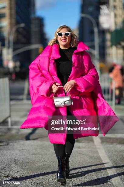 Guest wears a white vintage sunglasses, a black knees dress, black tights, an oversized neon pink oversized long puffer jacket, a silver shiny...