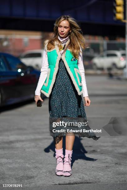 Guest wears a white turtleneck pullover, a silver large chain with yellow and brown butterfly pendant necklace, a green mint with white sheep borders...