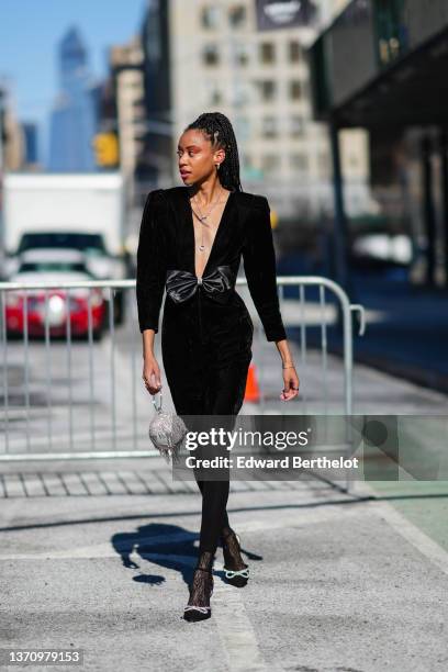 Guest wears gold earrings, a silver chain with diamonds pendant necklace, a black velvet long V-neck / long sleeves / large satin knot belt short...