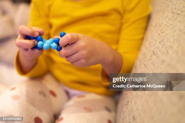 young mixed-race girl holding building toy sitting on sofa at home - people of different races stock pictures, royalty-free photos & images