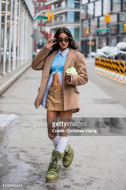 Guest is seen wearing blue white cropped blouse, brown jacket, beige mini skirt, white knee socks, sunglasses, mint bag, moon boots in green outside...
