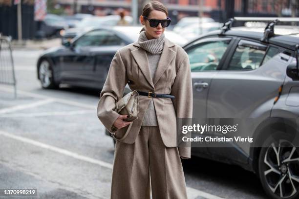 Guest is seen wearing grey turtleneck, brown belted blazer, wide leg pants, clutch, sunglasses outside Prabal Gurung during New York Fashion Week on...