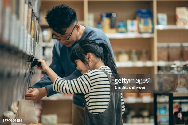 asiatischer vater und tochter kaufen im umweltfreundlichen laden, bildungskonzept ein - asian family shopping stock-fotos und bilder