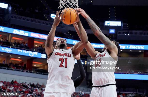 Sydney Curry and Dre Davis of the Louisville Cardinals reach for a rebound against the Miami Hurricanes at KFC YUM! Center on February 16, 2022 in...