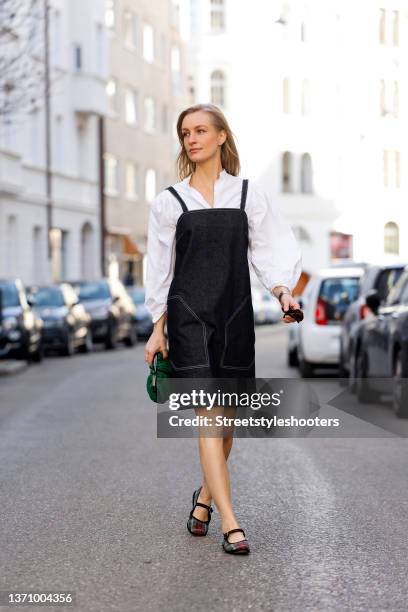 Influencer and model Marlies Pia Pfeifhofer wearing a white vintage blouse, a black denim jeans dress by Max Mara, a green clutch by Max Mara Weekend...