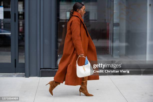 Guest is seen wearing rust brown coat, red turtleneck, denim jeans, white back, knee high suede boots outside Prabal Gurung during New York Fashion...