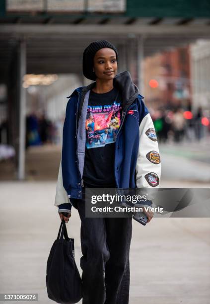 Model seen wearing college sports jacket New England Patriots 3x Super Bowl champions, tshirt with print, hoody, black pants, bag, beanie outside...