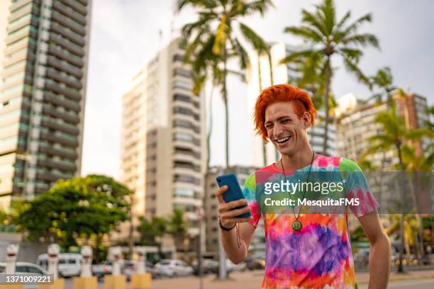 uomo dai capelli rossi che usa lo smartphone sul lungomare - lgbt mobile foto e immagini stock