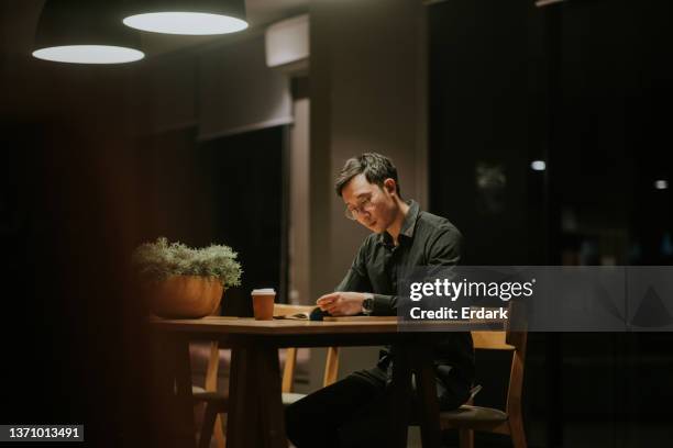 routine nocturne d’étudiant diplômé lisant un livre la nuit dans l’espace de co-working de son appartement. - master class photos et images de collection