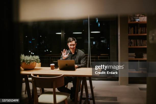 trabajando hasta tarde con distanciamiento social, empresario teniendo una reunión de videoconferencia con un cliente extranjero. - masters degree fotografías e imágenes de stock