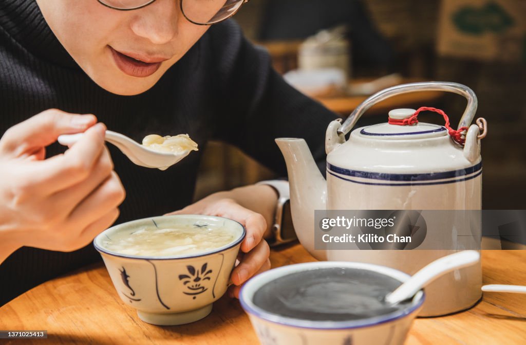 Asian woman enjoying traditional Chinese dessert lotus seed, lily snow fungus sweet soup (蓮子雪耳百合糖水)