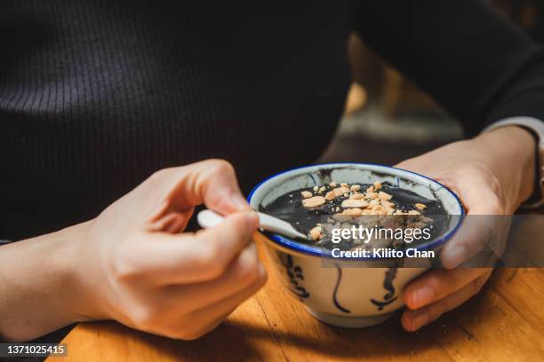 asian woman enjoying traditional chinese dessert black sesame paste soup (黑芝麻糊) - sesame stock pictures, royalty-free photos & images