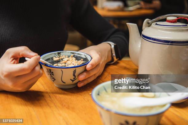 asian woman enjoying traditional chinese dessert black sesame paste soup (黑芝麻糊) - chinese soup bildbanksfoton och bilder