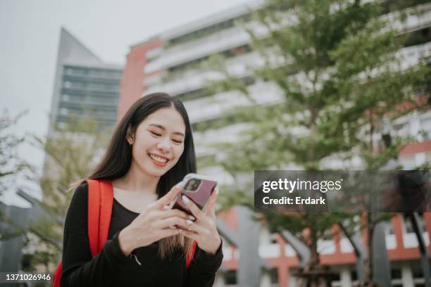 asian girl trying message with her friend on her smart phone. - school life balance stock pictures, royalty-free photos & images