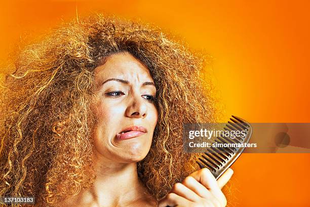 woman with frizzy and curly hair looking at a comb - frizzy 個照片及圖片檔