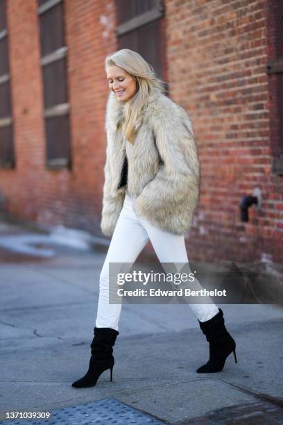 Kate Davidson Hudson wears a beige oversized fur coat, a white t-shirt, white denim skinny pants, black suede pointed heels knees boots / ankle...