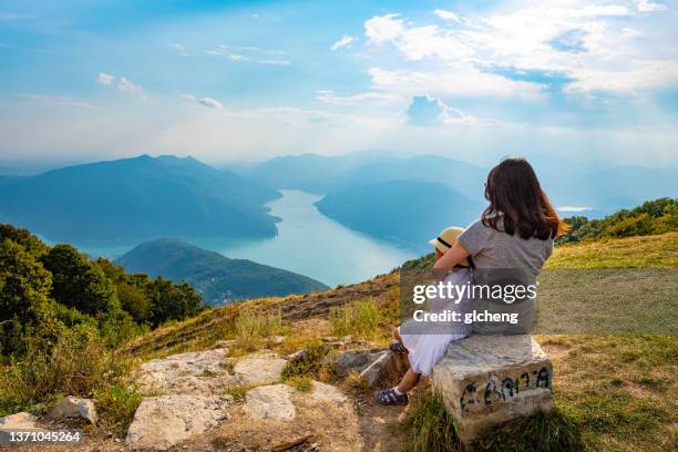 mother and daughter looking at view of lake lugano, balcone d'italia, italy - italien familie stock-fotos und bilder