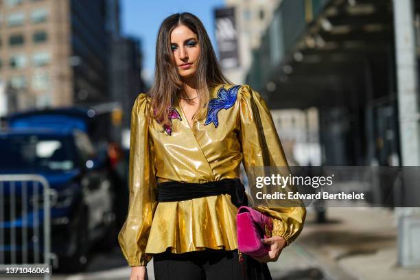 Guest wears a silver necklace, a gold shiny with red and navy blue embroidered sequined print pattern yoke puffy sleeves blouse, a black velvet belt,...