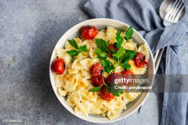 overhead view of a bowl of farfalle pasta with roasted tomatoes and coriander - cherry tomato stock-fotos und bilder