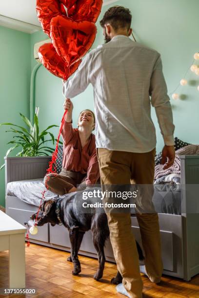 giving her bunch of red heart shaped balloons on valentine's day - valentine's day home stock pictures, royalty-free photos & images