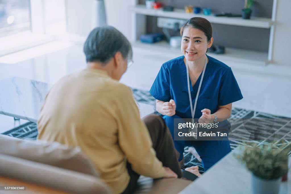 Asian Chinese female physiologist home caregiver encouraging senior woman exercising with her legs cycling