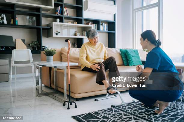 asian chinese female physiologist home caregiver encouraging senior woman exercising with her legs cycling - patient on ventilator stock pictures, royalty-free photos & images