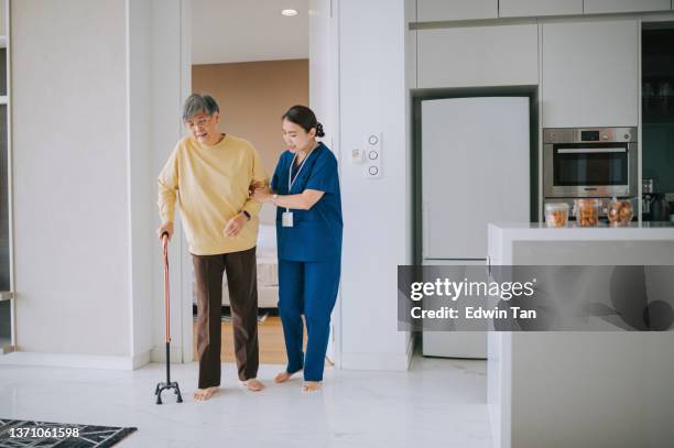 enfermera china asiática ayudando a una mujer mayor a practicar caminar con bastón en la sala de estar. paciente mayor con bastidor y enfermera - stick fotografías e imágenes de stock