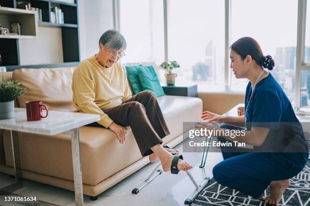 asian chinese female physiologist home caregiver encouraging senior woman exercising with her legs cycling - terapia ocupacional imagens e fotografias de stock