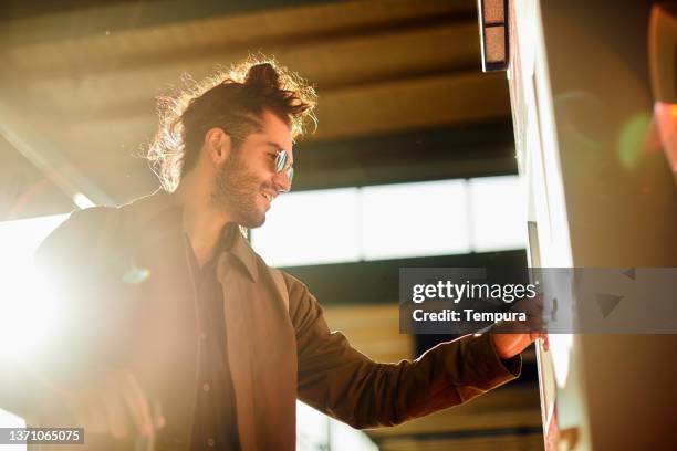 ein junger mann kauft an einem sonnigen nachmittag ein u-bahn-ticket. - train station stock-fotos und bilder