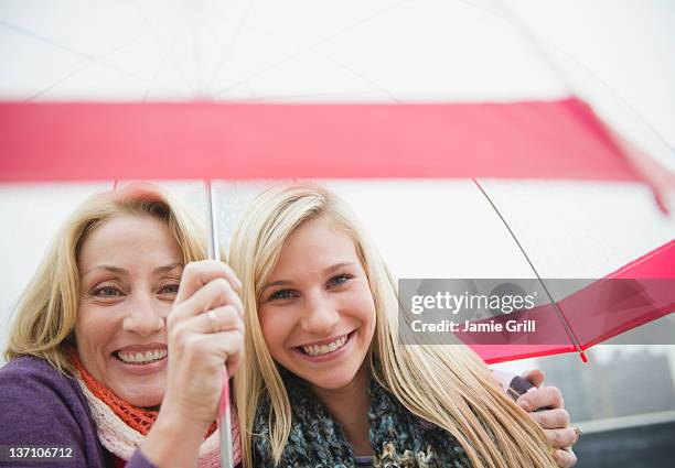 mother and daughter under umbrella, smiling - mother protecting from rain stockfoto's en -beelden