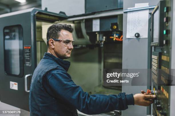 male apprentice engineer working with cnc machine in factory - cnc maschine stock pictures, royalty-free photos & images