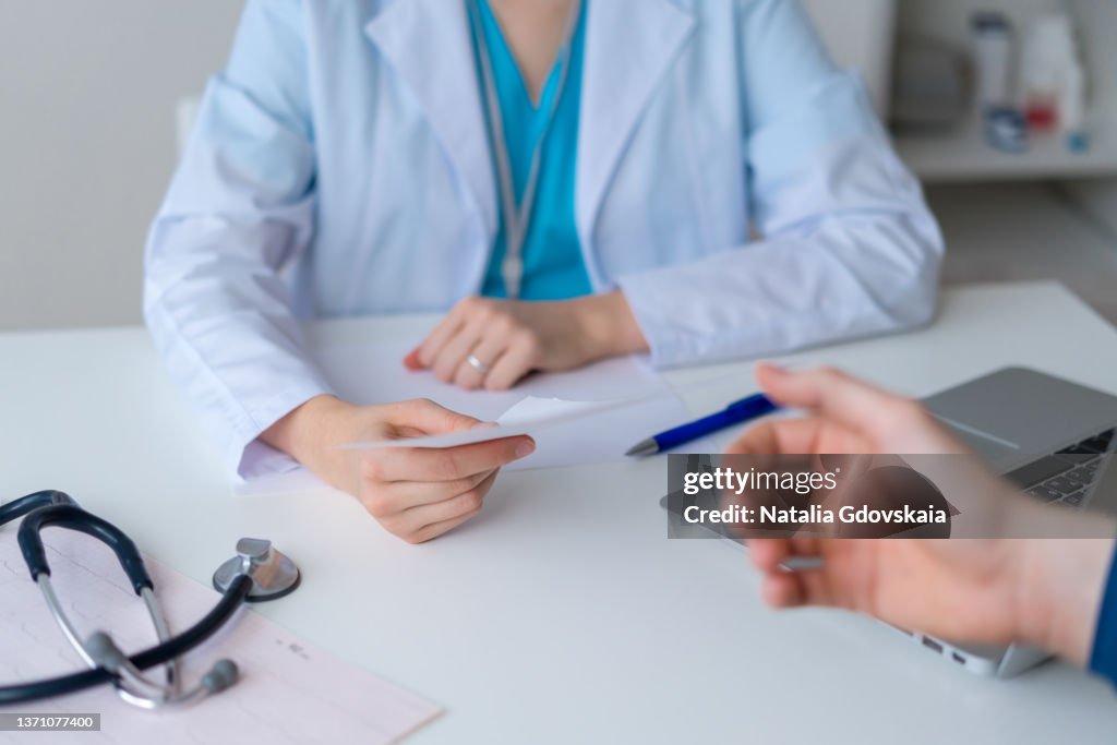 Unrecognizable doctor prescribing pharmacy to patient. Male hand reaching for piece of paper