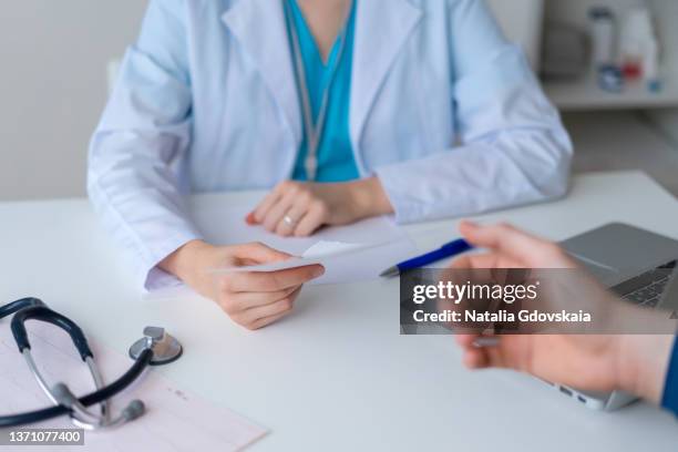 unrecognizable doctor prescribing pharmacy to patient. male hand reaching for piece of paper - medical imagens e fotografias de stock