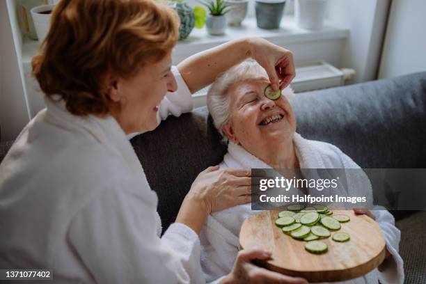 senior mother with mature daughter in bathrobes having spa day at home together. - woman facial expression stock pictures, royalty-free photos & images