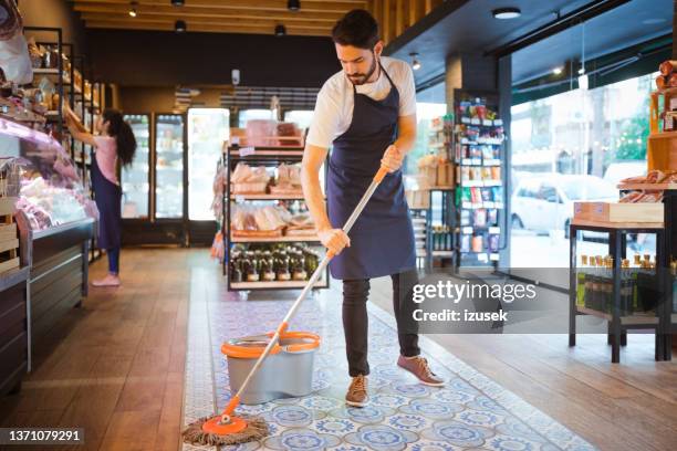 male salesman mopping floor at convenience store - corner shop stock pictures, royalty-free photos & images