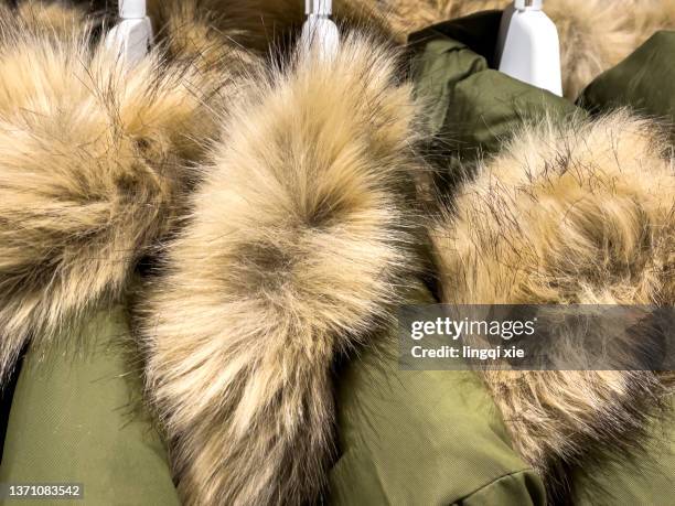 coats with a hairy collar hung on the shelf - fur jacket fotografías e imágenes de stock