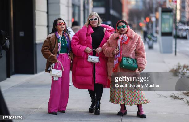 Greivy wears: dark green sunglasses, a red-pink-green flower print pattern oversized silk scarf, a pale orange fluffy oversized winter coat, a pale...
