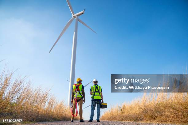 two engineers at wind farm, walking together, rear view - macacão preto imagens e fotografias de stock