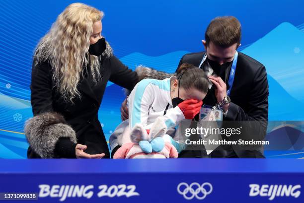 Kamila Valieva of Team ROC reacts to their score with choreographer Daniil Gleikhengauz and coach Eteri Tutberidze after the Women Single Skating...