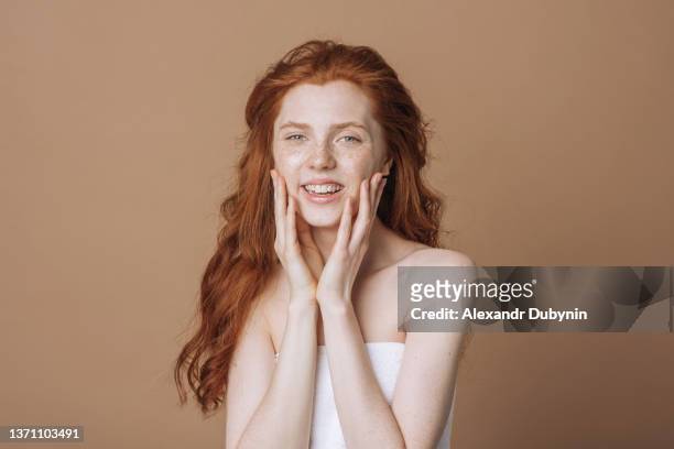 happy redhead young woman with freckles and clean skin smiling looking at camera. beauty and health concept - blank face stock-fotos und bilder