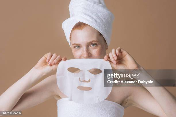 happy woman holds in her hands a fabric mask for facial care. cosmetics and skin care concept - cloth mask 個照片及圖片檔