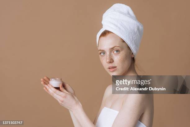 beautiful woman holding a jar of cream and looking at the camera. cosmetics and body care concept - lap body area stock-fotos und bilder