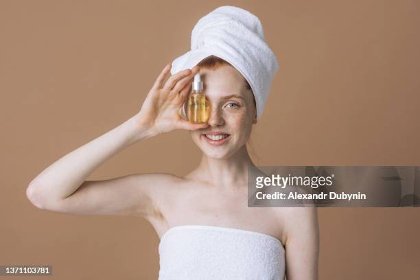happy woman holding face oil bottle in her hands.cosmetics and body care concept - 血清樣本 個照片及圖片檔