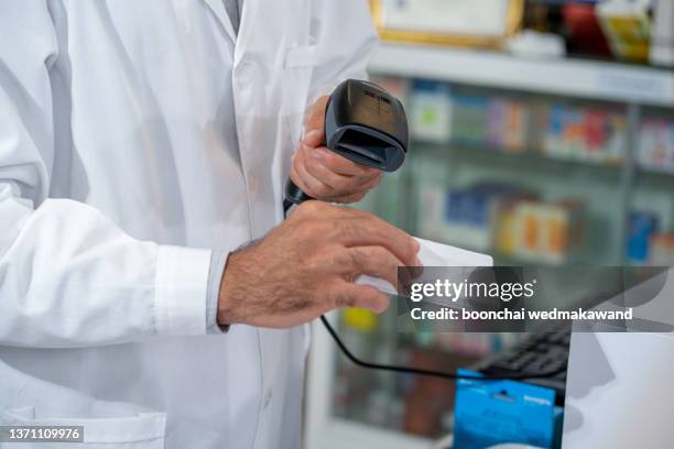 close up hands of pharmacist scanning barcode on product in pharmacy. - medical scanner stock pictures, royalty-free photos & images