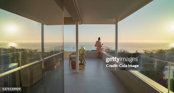 woman relaxing on sunny balcony with sunset ocean view - south africa wine stock pictures, royalty-free photos & images