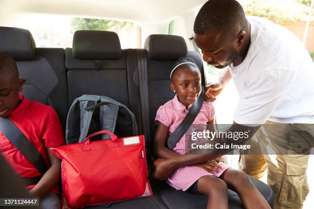 father fastening seat belt for daughter in back seat of car - fastening stock pictures, royalty-free photos & images
