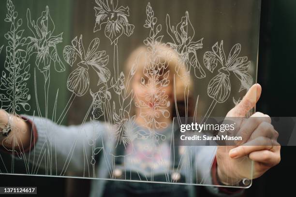 designer holding up etched glass panel - femalefocuscollection stock pictures, royalty-free photos & images